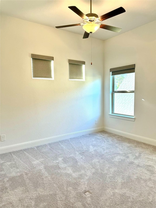 carpeted spare room featuring a ceiling fan and baseboards