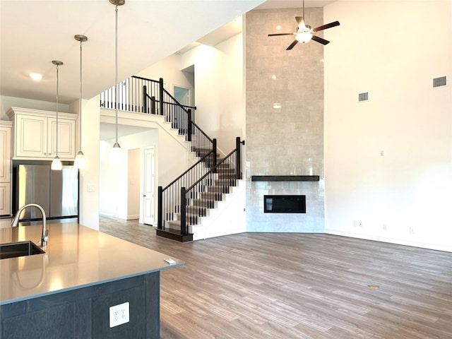 unfurnished living room with dark wood-type flooring, a high ceiling, a fireplace, a sink, and stairs