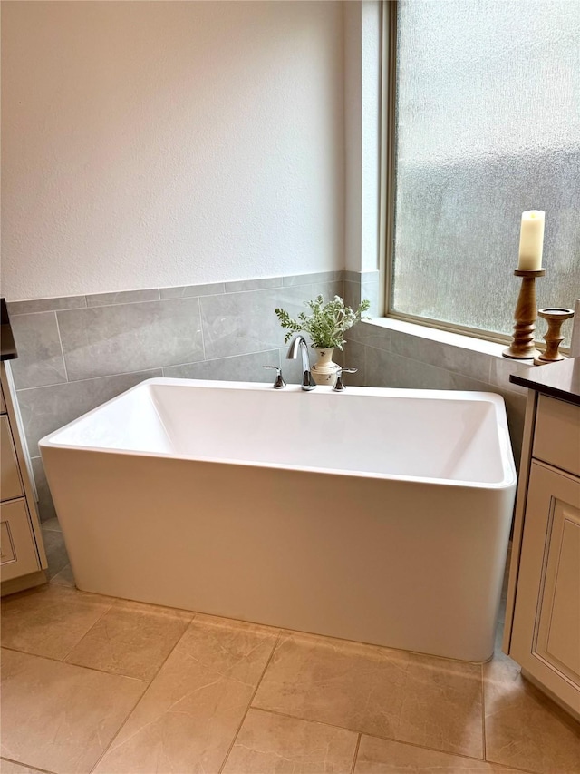 full bath with a freestanding bath, tile walls, and vanity