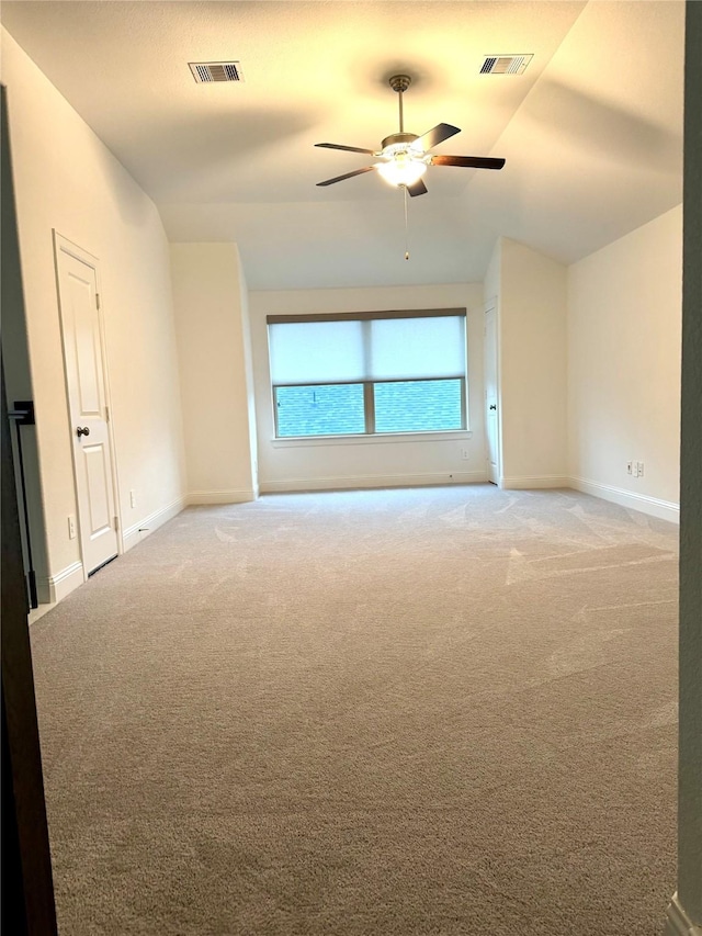 carpeted spare room featuring lofted ceiling, baseboards, visible vents, and ceiling fan