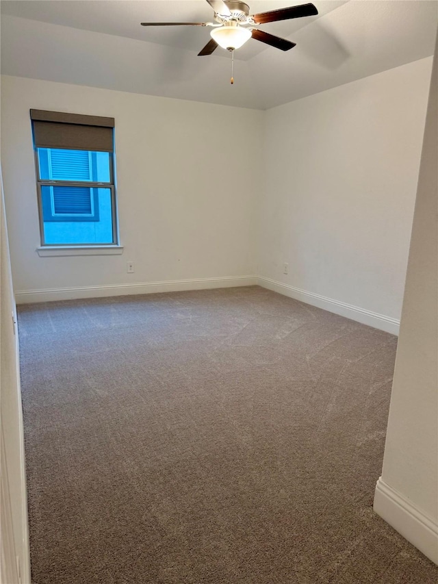 carpeted empty room featuring baseboards and a ceiling fan