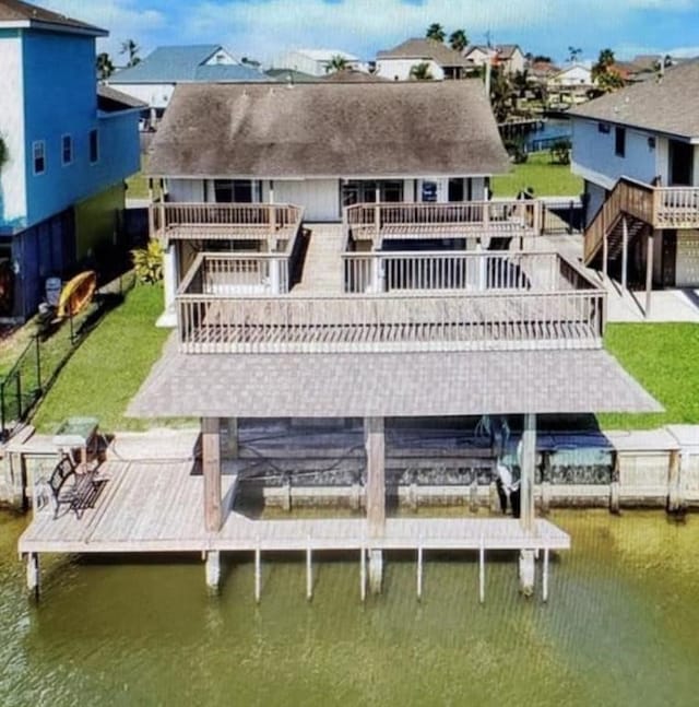 back of property with a deck with water view and a lawn