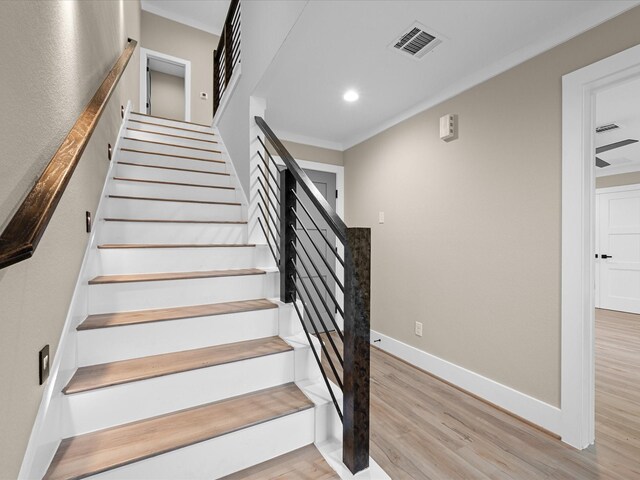 stairs with hardwood / wood-style flooring and ornamental molding