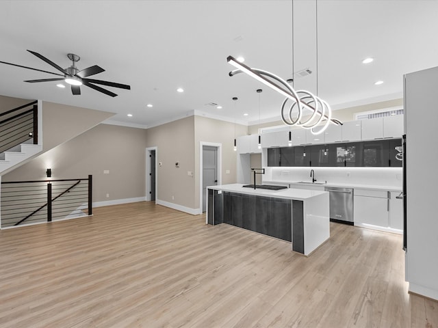 kitchen with decorative light fixtures, stainless steel dishwasher, white cabinets, and a center island with sink