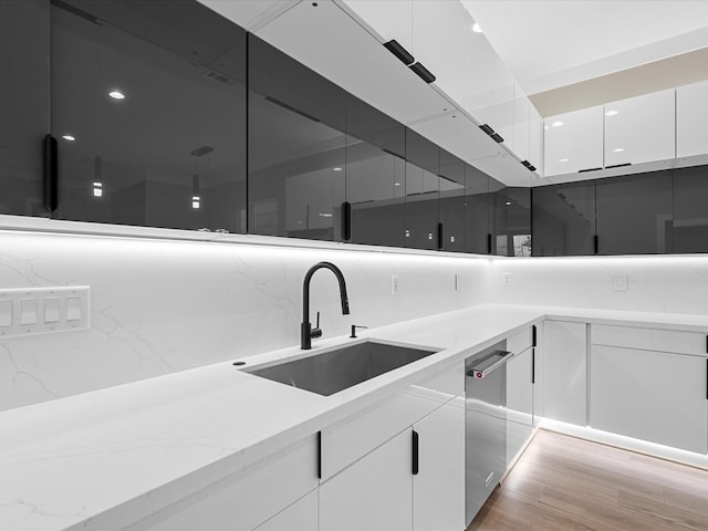 kitchen featuring sink, white cabinets, tasteful backsplash, light stone counters, and light hardwood / wood-style floors