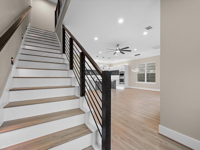 staircase with wood-type flooring and ceiling fan