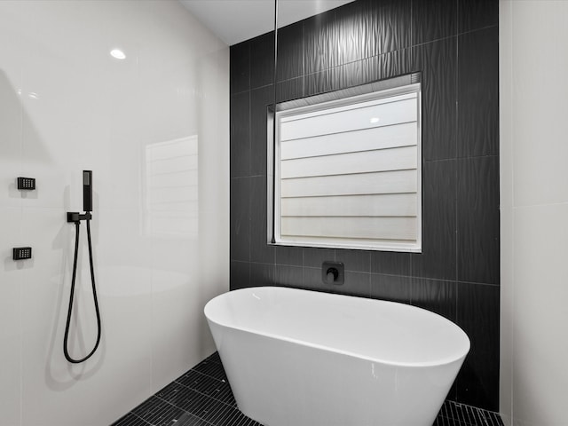 bathroom with a washtub, tile patterned floors, and tile walls