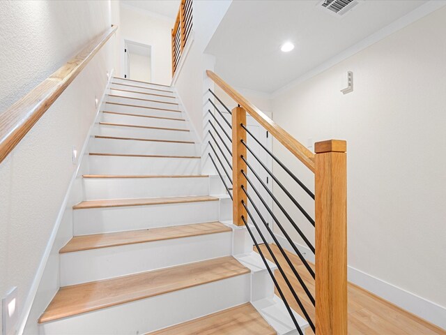 stairs featuring hardwood / wood-style flooring and ornamental molding