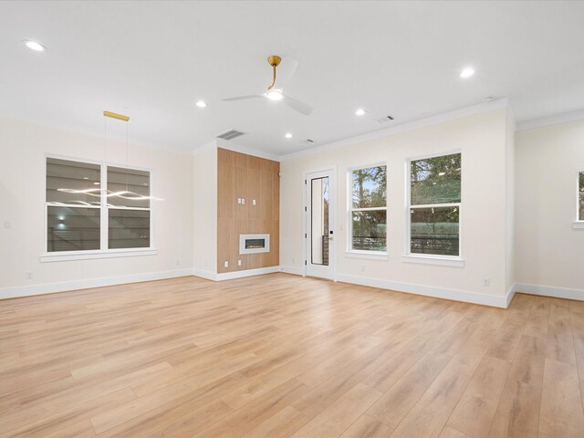 unfurnished living room with light hardwood / wood-style floors, a tile fireplace, crown molding, and ceiling fan