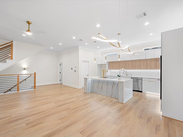 kitchen with dishwasher, white cabinetry, hanging light fixtures, light wood-type flooring, and a center island with sink