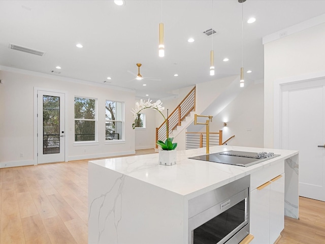 kitchen featuring a spacious island, pendant lighting, black electric stovetop, and stainless steel microwave