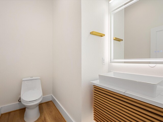 bathroom with hardwood / wood-style flooring, toilet, and vanity