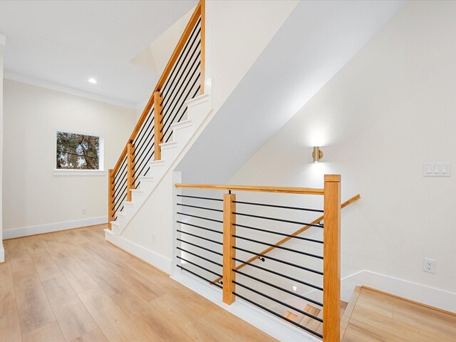 stairway featuring wood-type flooring and ornamental molding