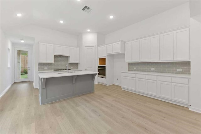 kitchen with oven, white cabinetry, and light wood-type flooring