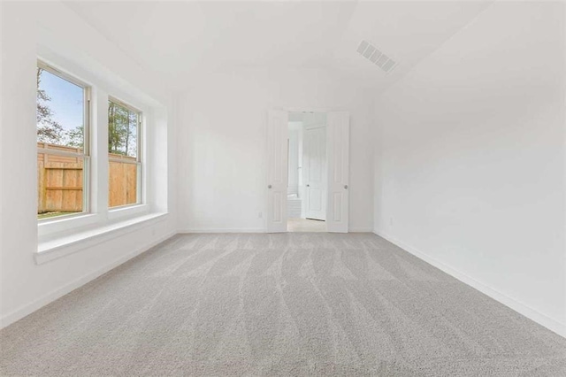 carpeted empty room featuring vaulted ceiling