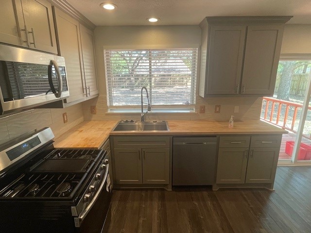 kitchen with gray cabinetry, stainless steel appliances, sink, and dark hardwood / wood-style floors