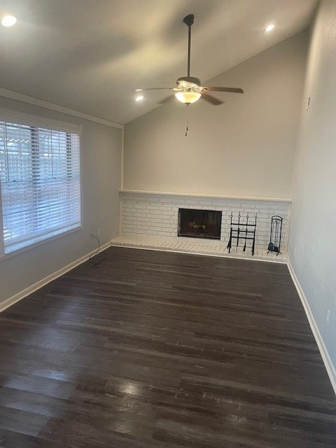 unfurnished living room featuring lofted ceiling, dark wood-type flooring, ornamental molding, a brick fireplace, and ceiling fan