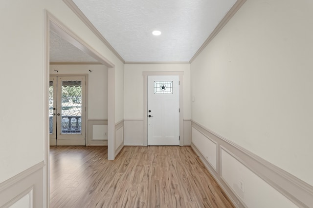 foyer with crown molding, a textured ceiling, and light hardwood / wood-style flooring