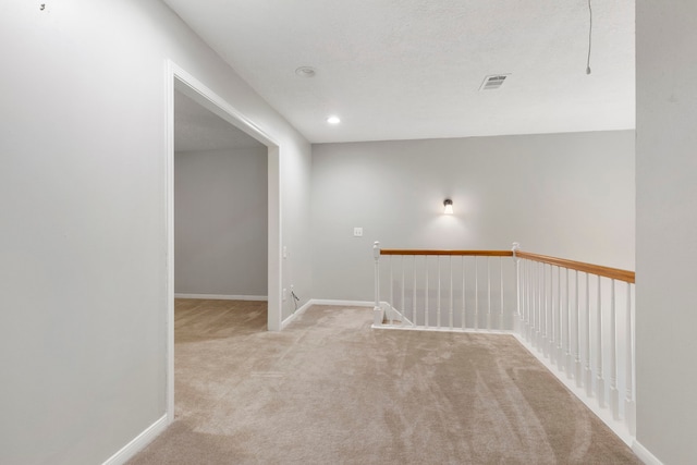 hallway with a textured ceiling and light carpet