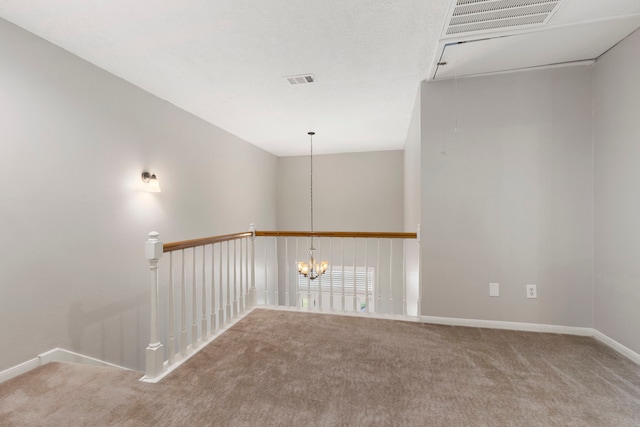 carpeted empty room with a notable chandelier