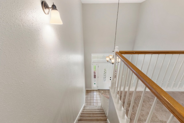 stairs featuring tile patterned floors and an inviting chandelier