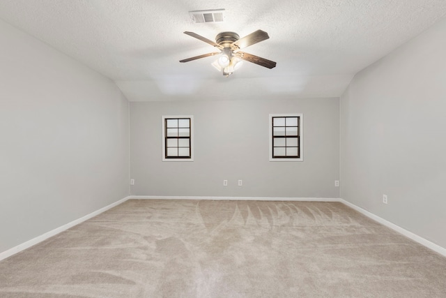 empty room featuring lofted ceiling, a textured ceiling, light carpet, and ceiling fan