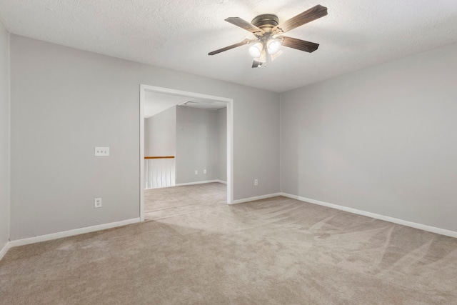 spare room featuring a textured ceiling, light colored carpet, and ceiling fan