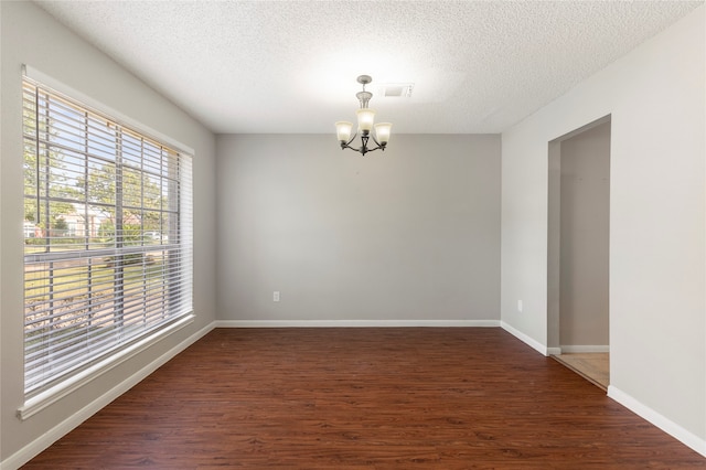 unfurnished room with dark hardwood / wood-style flooring, a chandelier, and a textured ceiling