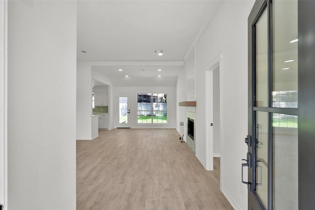 foyer featuring crown molding, a fireplace, baseboards, and light wood-style floors