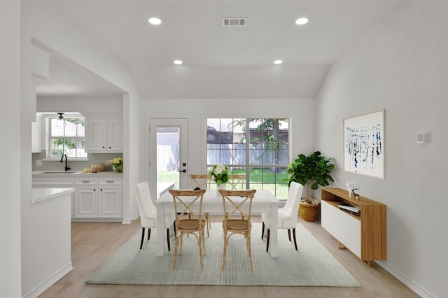 dining room featuring sink, ceiling fan, vaulted ceiling, and light wood-type flooring