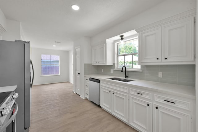 kitchen with a healthy amount of sunlight, appliances with stainless steel finishes, sink, and white cabinets