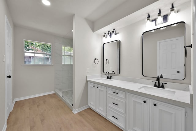 bathroom featuring a tile shower, vanity, and wood-type flooring