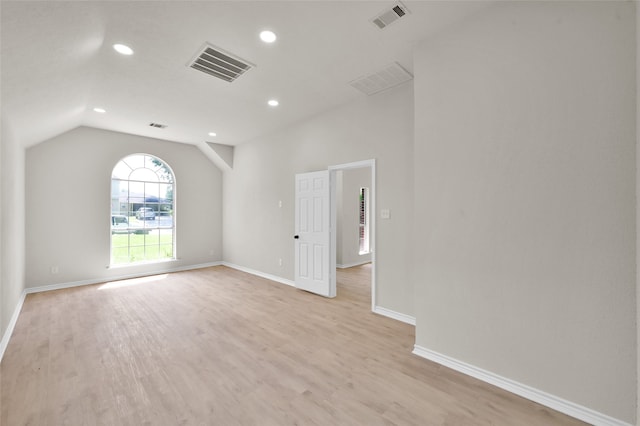 spare room with lofted ceiling and light wood-type flooring