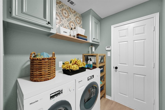 laundry room with washer and dryer, cabinets, and light hardwood / wood-style floors