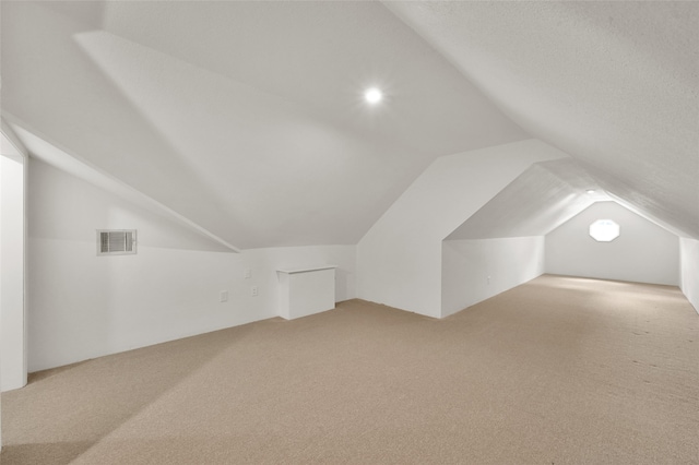 additional living space featuring lofted ceiling and carpet