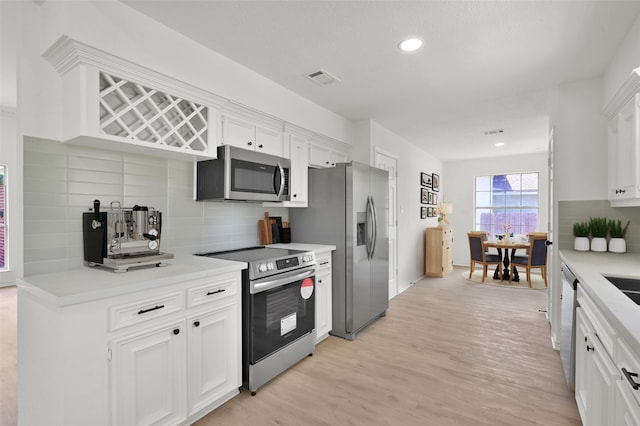 kitchen featuring light hardwood / wood-style floors, white cabinets, stainless steel appliances, and backsplash