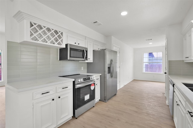 kitchen featuring appliances with stainless steel finishes, decorative backsplash, white cabinets, and light hardwood / wood-style floors