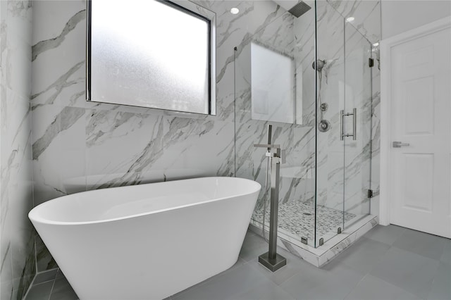 bathroom featuring plus walk in shower, tile patterned floors, and tile walls