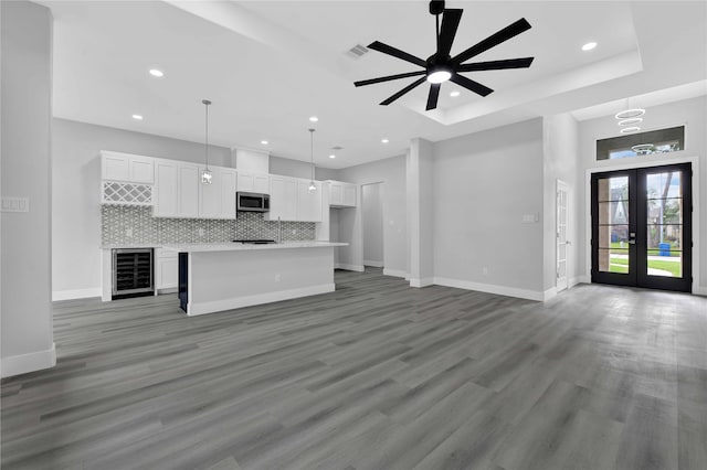 unfurnished living room featuring wine cooler, french doors, hardwood / wood-style flooring, and ceiling fan