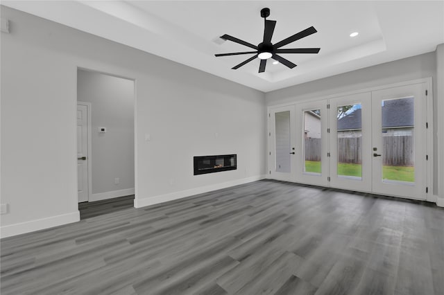 unfurnished living room with french doors, ceiling fan, a raised ceiling, and wood-type flooring