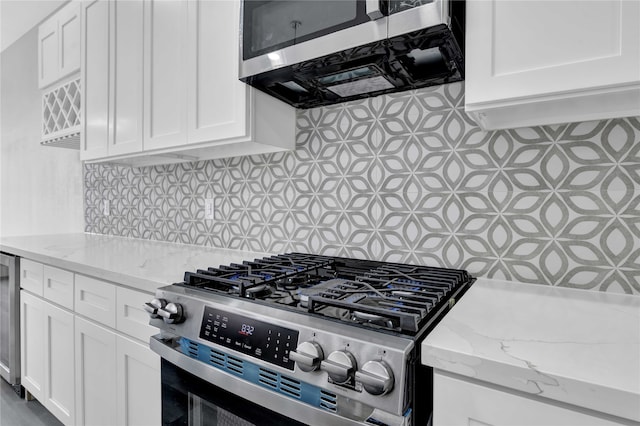 kitchen featuring backsplash, appliances with stainless steel finishes, light stone counters, and white cabinets