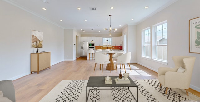 dining area featuring ornamental molding, a chandelier, and light wood-type flooring