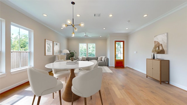 dining area featuring crown molding, light wood-type flooring, and ceiling fan with notable chandelier