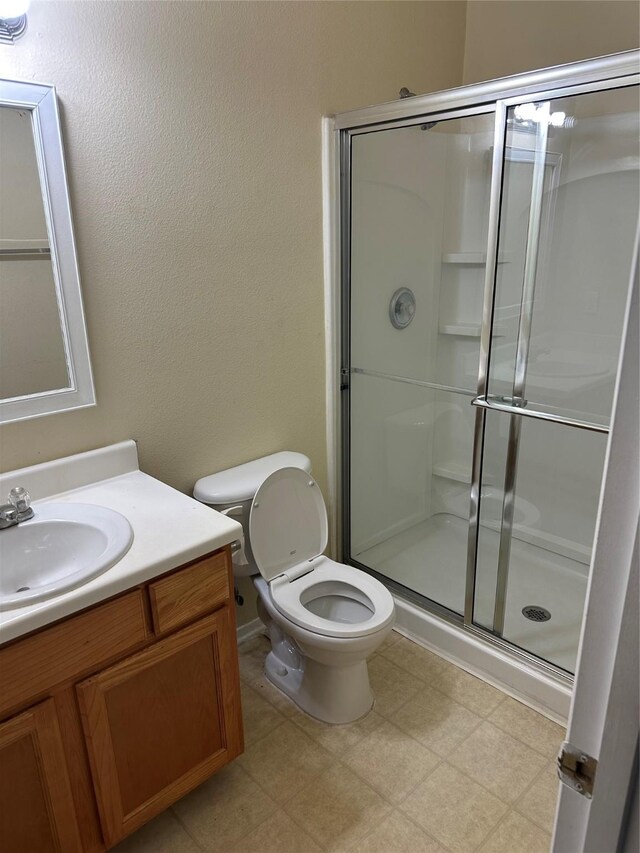 bathroom featuring vanity, a shower with shower door, and toilet