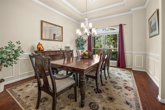 dining area with ornamental molding, a notable chandelier, a tray ceiling, and dark hardwood / wood-style flooring