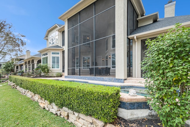 back of house with a lawn and a sunroom