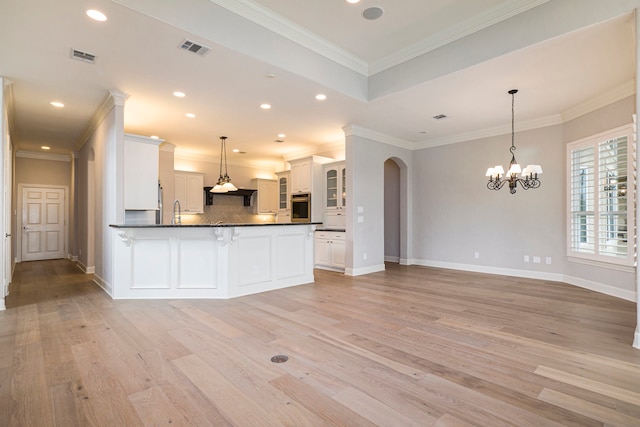 kitchen featuring oven, crown molding, white cabinets, and pendant lighting