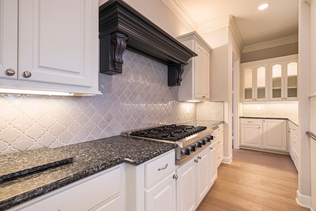 kitchen with tasteful backsplash, stainless steel gas stovetop, white cabinetry, light hardwood / wood-style flooring, and custom range hood