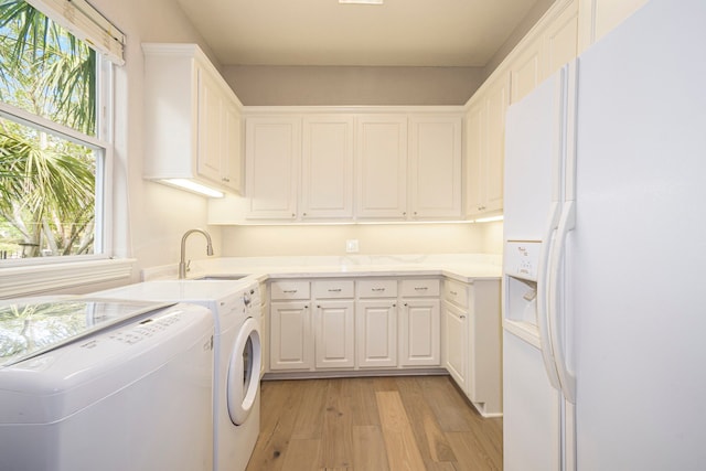 clothes washing area with sink, light hardwood / wood-style flooring, and separate washer and dryer