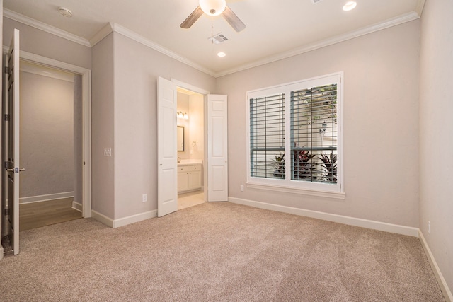 unfurnished bedroom with ornamental molding, ensuite bath, carpet, and ceiling fan